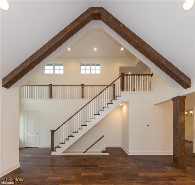 staircase featuring hardwood / wood-style flooring, high vaulted ceiling, and decorative columns