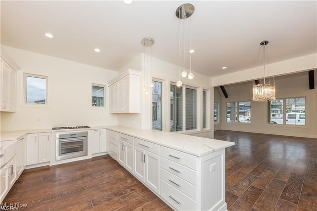 kitchen with kitchen peninsula, white cabinets, hanging light fixtures, dark hardwood / wood-style flooring, and stainless steel appliances