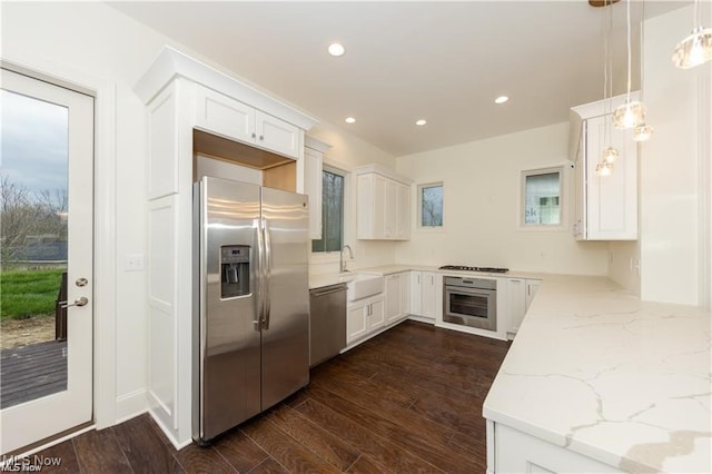 kitchen with dark wood-type flooring, stainless steel appliances, sink, decorative light fixtures, and white cabinets