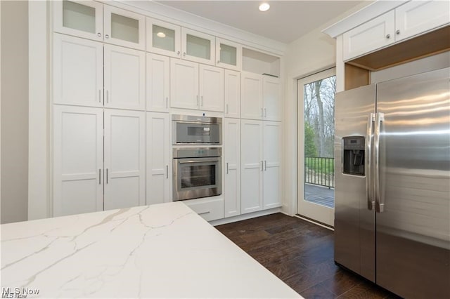 kitchen with light stone counters, stainless steel appliances, dark hardwood / wood-style flooring, and white cabinets