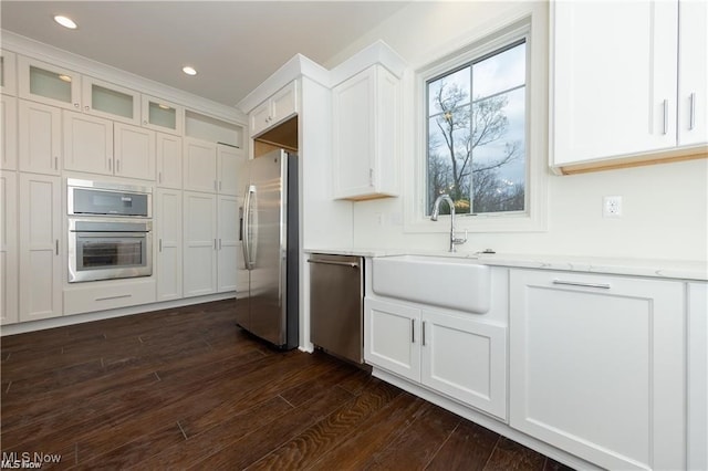 kitchen featuring dark hardwood / wood-style floors, sink, white cabinetry, appliances with stainless steel finishes, and light stone counters