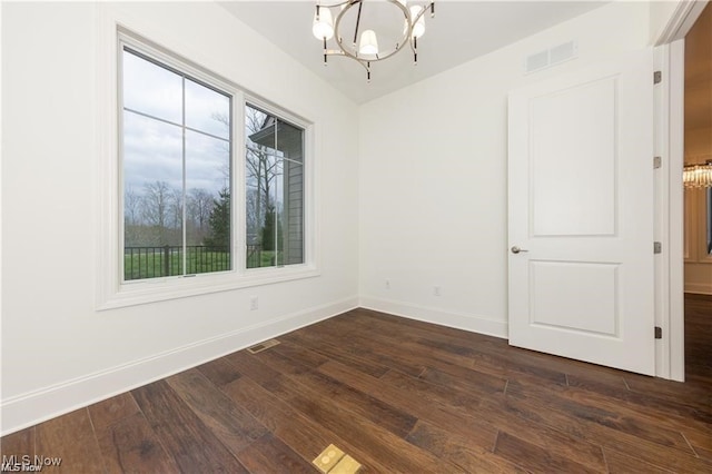 spare room with a chandelier and dark hardwood / wood-style flooring