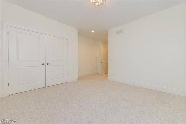 unfurnished bedroom with a closet and light colored carpet