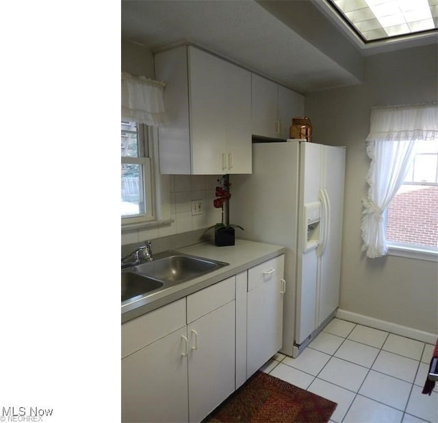 kitchen with tasteful backsplash, white fridge with ice dispenser, white cabinetry, light tile patterned flooring, and sink