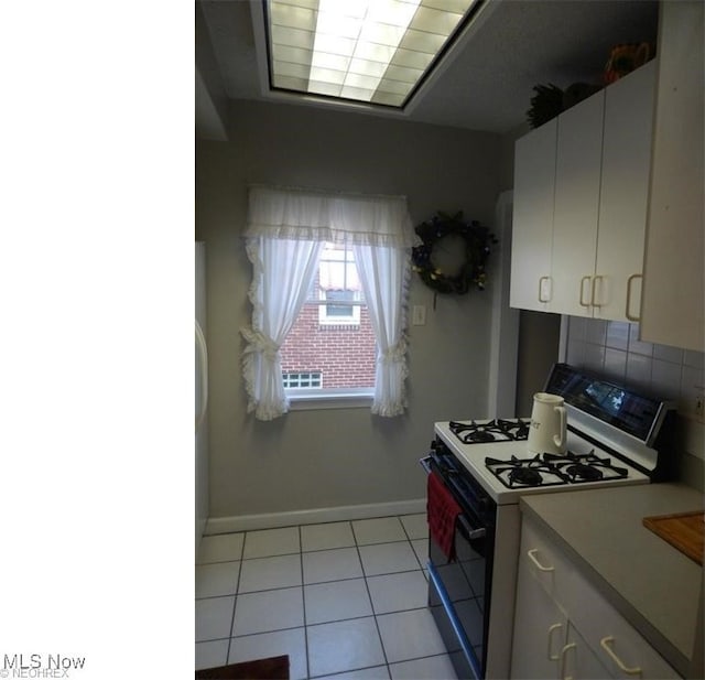 kitchen with white cabinetry, white gas range oven, decorative backsplash, and light tile patterned floors