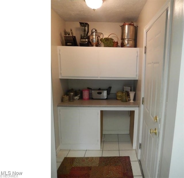 kitchen with white cabinets, a textured ceiling, and light tile patterned flooring