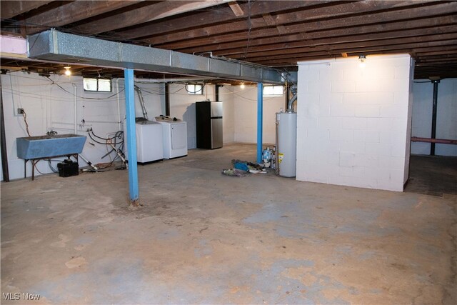 basement featuring sink, gas water heater, washing machine and dryer, and stainless steel refrigerator