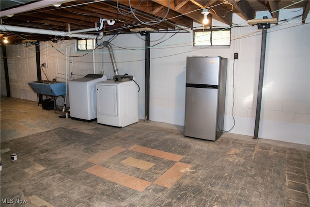 basement with washing machine and clothes dryer, stainless steel fridge, and sink