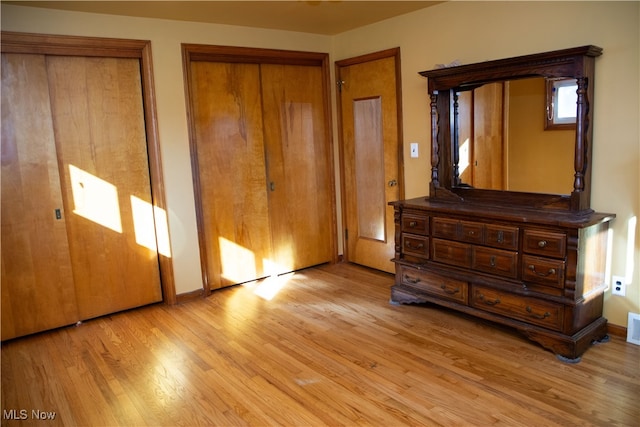 unfurnished bedroom featuring light hardwood / wood-style flooring and two closets