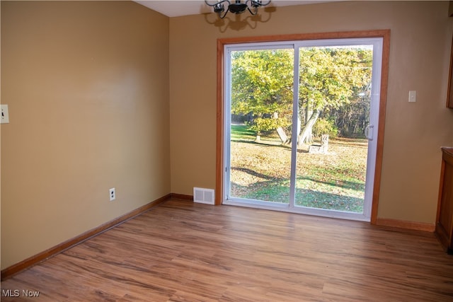 spare room with wood-type flooring and a chandelier