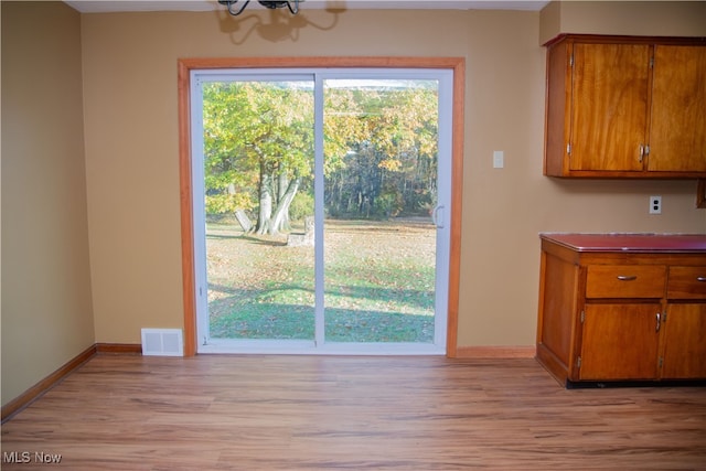 unfurnished dining area with light wood-type flooring and an inviting chandelier