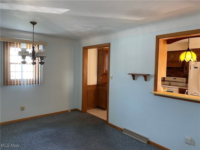 carpeted spare room featuring an inviting chandelier