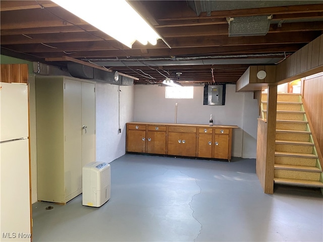 basement featuring electric panel and white fridge