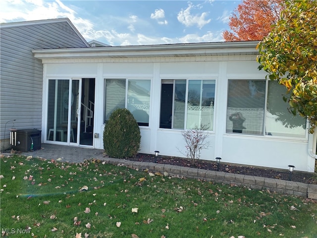 view of side of home with a sunroom and a yard