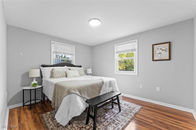 bedroom with dark hardwood / wood-style flooring and multiple windows