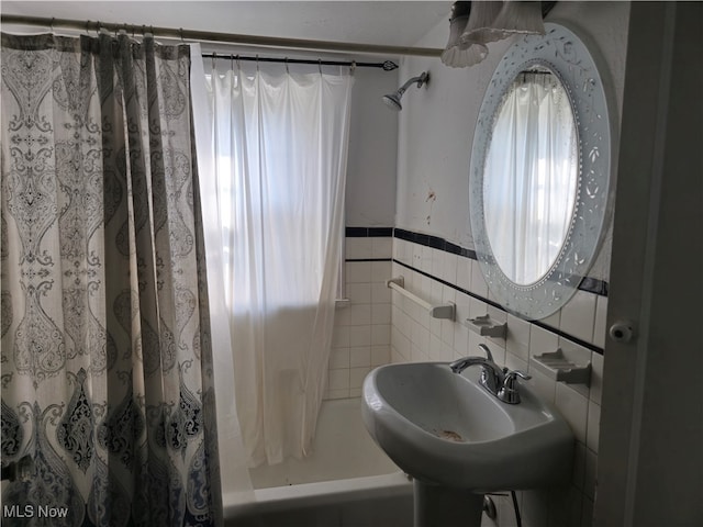 bathroom with tile walls, sink, and shower / bath combo with shower curtain