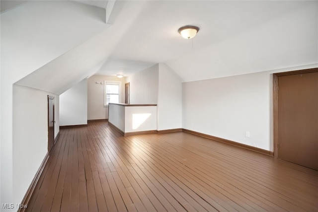 additional living space featuring lofted ceiling and dark hardwood / wood-style floors