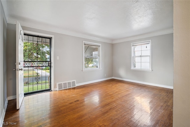 unfurnished room with ornamental molding, wood-type flooring, and plenty of natural light