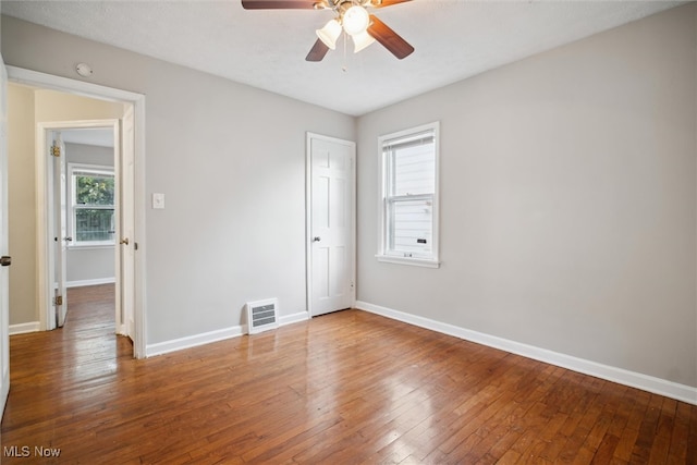 unfurnished bedroom with multiple windows, wood-type flooring, and ceiling fan