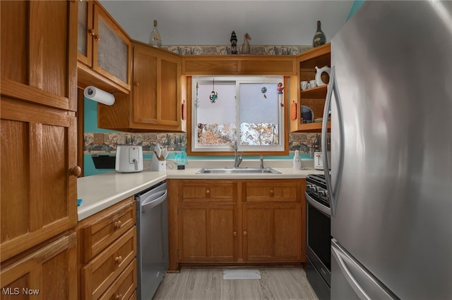 kitchen with light hardwood / wood-style floors, stainless steel appliances, sink, and backsplash