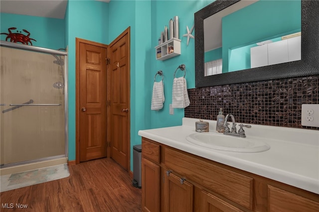 bathroom featuring toilet, wood-type flooring, backsplash, vanity, and an enclosed shower