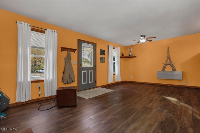 interior space with a wall mounted AC, ceiling fan, and dark hardwood / wood-style flooring