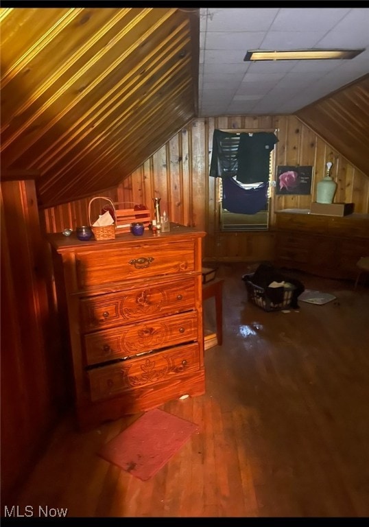 additional living space with wood-type flooring, vaulted ceiling, and wooden walls