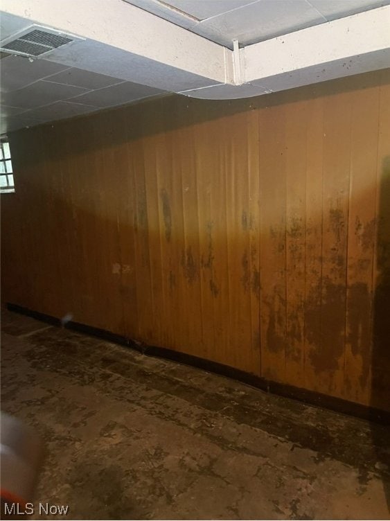 basement featuring a paneled ceiling and wood walls