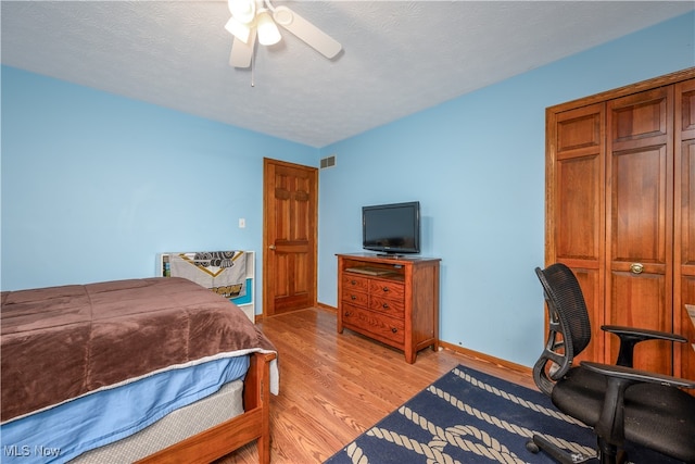 bedroom with a textured ceiling, light hardwood / wood-style floors, and ceiling fan