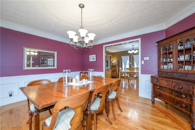 dining area featuring crown molding, a textured ceiling, a chandelier, and light wood-type flooring