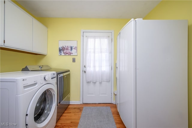 laundry area featuring cabinets, light hardwood / wood-style flooring, and independent washer and dryer