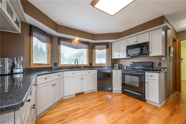 kitchen with light hardwood / wood-style flooring, sink, black appliances, white cabinets, and a textured ceiling