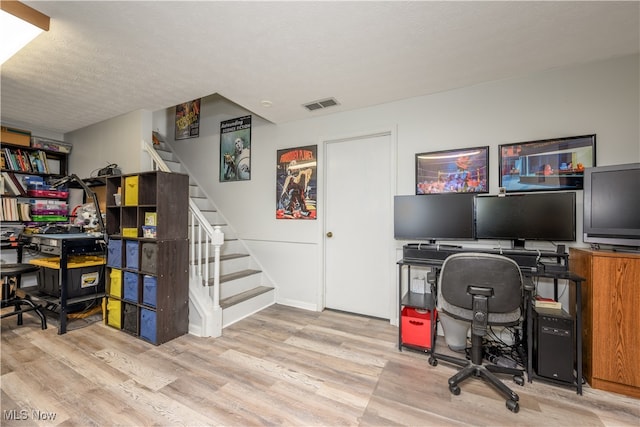 office with light hardwood / wood-style flooring and a textured ceiling