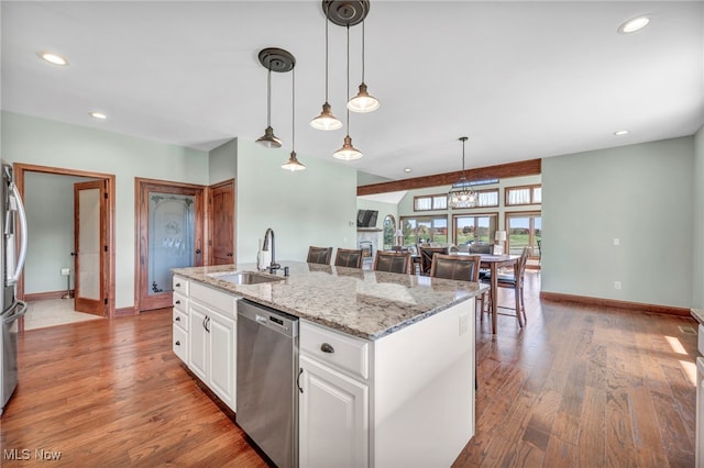 kitchen featuring wood-type flooring, stainless steel appliances, white cabinetry, sink, and a kitchen island with sink