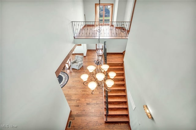 staircase with hardwood / wood-style floors and a notable chandelier