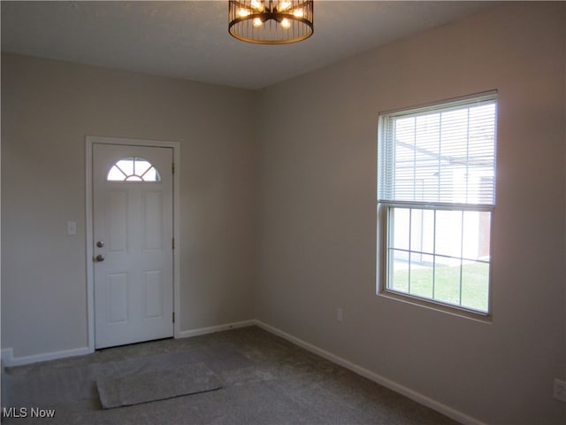 carpeted entryway with an inviting chandelier and plenty of natural light