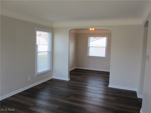 unfurnished room with dark wood-type flooring, a wealth of natural light, and crown molding