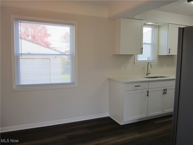 kitchen with dark wood-type flooring, stainless steel refrigerator, white cabinetry, and sink