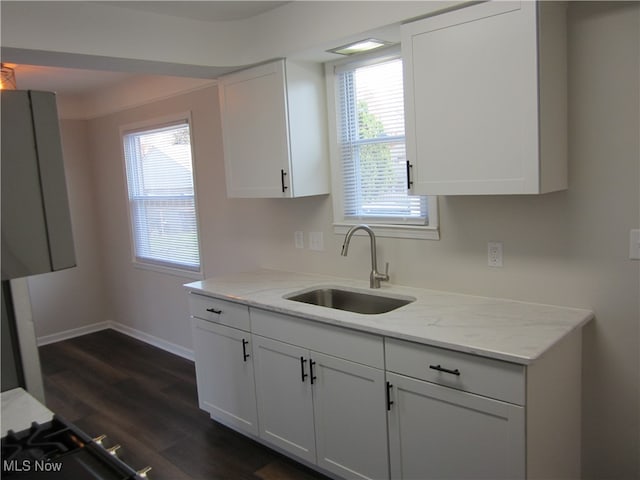 kitchen featuring dark wood-type flooring, white cabinetry, sink, and light stone countertops