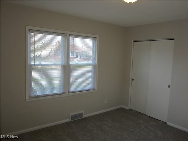 unfurnished bedroom featuring dark colored carpet and a closet