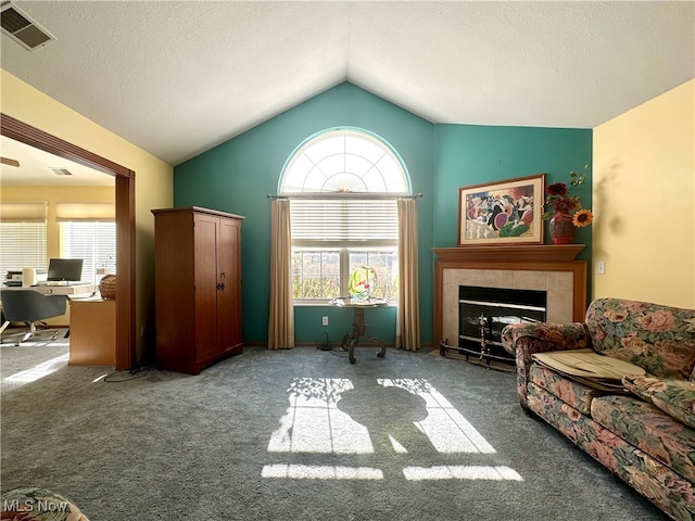 sitting room featuring a tiled fireplace, carpet, lofted ceiling, and plenty of natural light