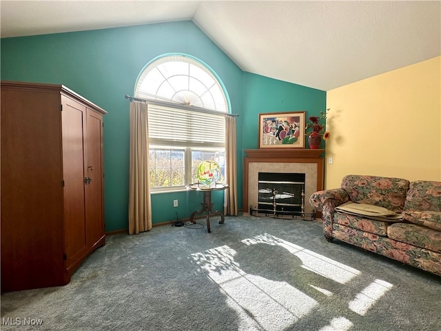 living room featuring a tiled fireplace, carpet flooring, and vaulted ceiling