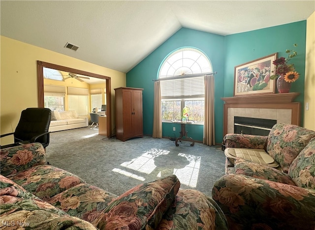 living room with lofted ceiling, carpet, a tiled fireplace, and ceiling fan