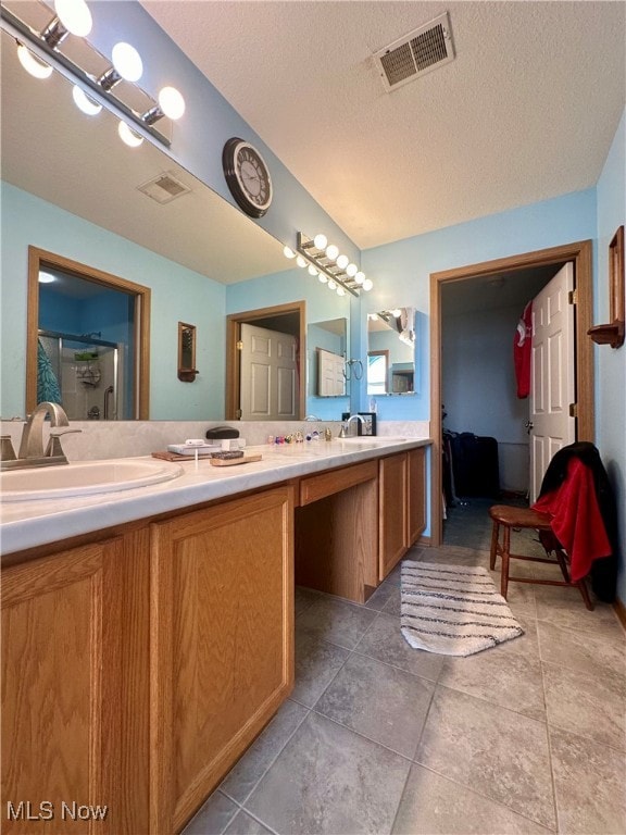 bathroom featuring a shower with door, a textured ceiling, tile patterned flooring, and vanity