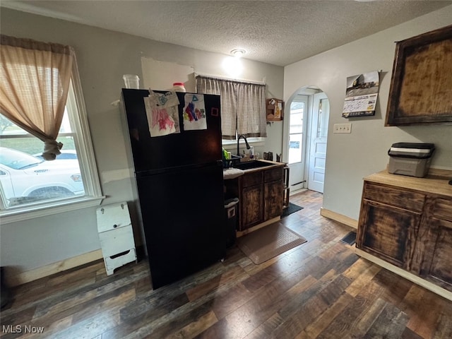 kitchen featuring dark hardwood / wood-style flooring, black fridge, a textured ceiling, dark brown cabinetry, and sink