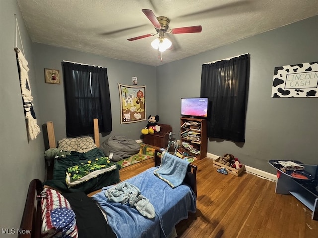 bedroom with a textured ceiling, hardwood / wood-style flooring, and ceiling fan