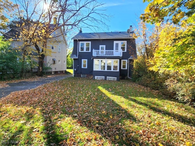 back of house featuring a balcony and a yard