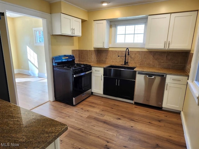 kitchen with light wood-type flooring, appliances with stainless steel finishes, decorative backsplash, sink, and white cabinets