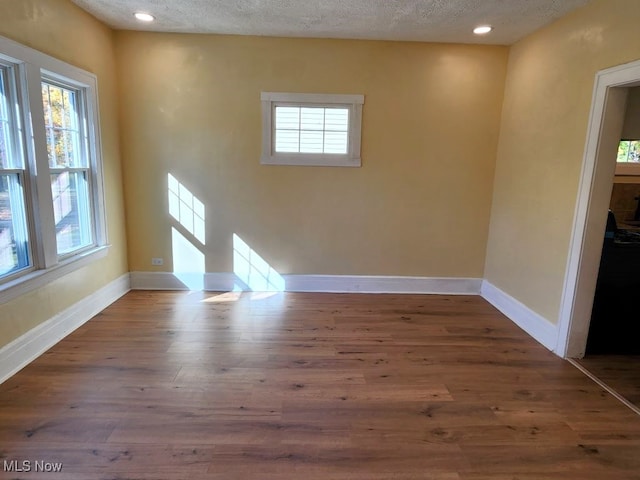 unfurnished room featuring wood-type flooring and a textured ceiling