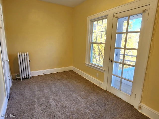 spare room with radiator and dark carpet